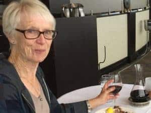 Marilyn Wood sits at a table with a glass of wine.