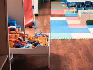 Photo of a kids play space. You can see toys and a colourful tiled rug.